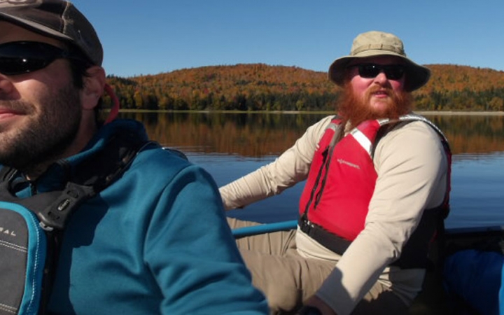 Two people sitting in a canoe smile at the camera. 